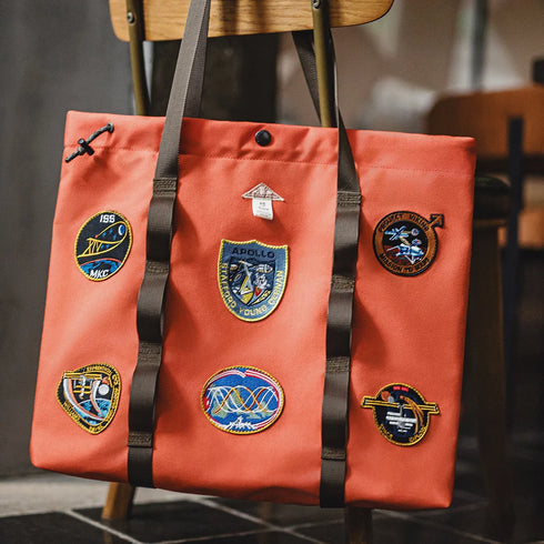 Orange tote bag with patches on a chair